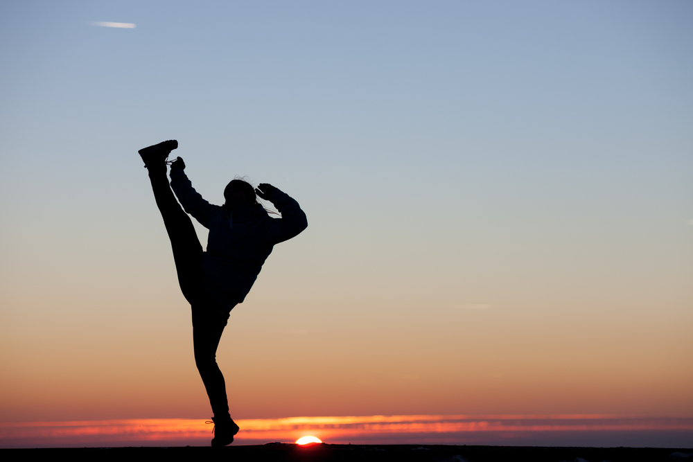 woman kicking sunset